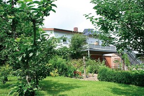 Ein Wohnhaus mit Garten und Holzzaun sowie ein Gebäude mit geneigtem Dach.