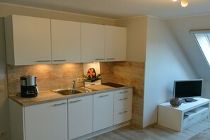 A modern kitchen with white cabinets, a coffee maker, and a sink. - Altschulze "Water Lily" (Schwielochsee OT Zaue)