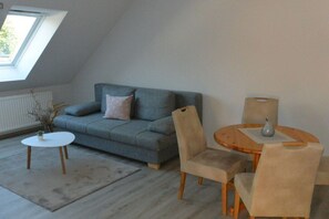 A room with a grey sofa, a round wooden table, and two chairs. - Altschulze "Water Lily" (Schwielochsee OT Zaue)