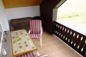 Uma pequena varanda com mesa, cadeiras e vista para o exterior.