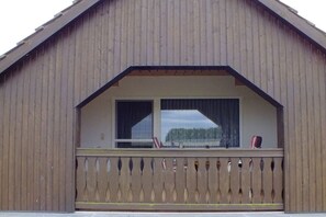 Ein Holzhaus mit Balkon und großem Fenster.