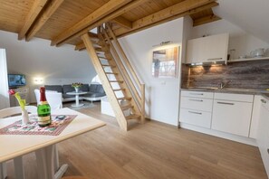 A loft-style apartment with a kitchen, dining area, and a staircase. - 4 in the country house “Am See” Neuensien (Ostseebad Sellin)