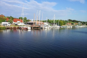 A marina with boats docked, a building with a red roof, and a truck parked nearby. - 4 in the country house “Am See” Neuensien (Ostseebad Sellin)