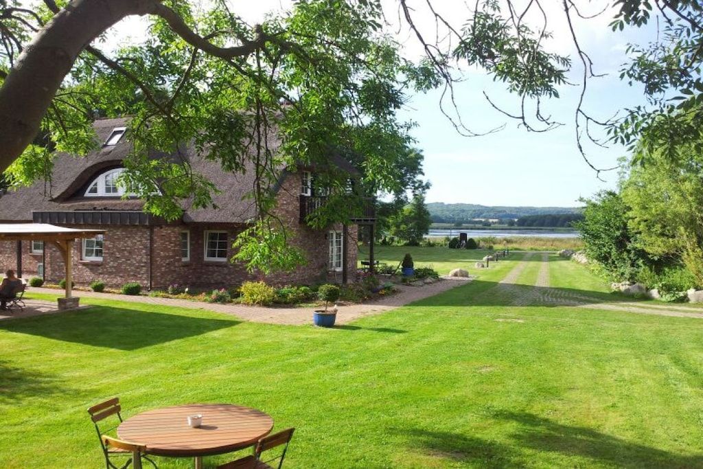A house with a brick exterior, a lawn, and a view of a body of water.
