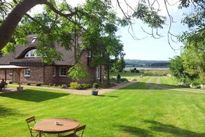 A house with a brick exterior, a lawn, and a view of a body of water. - 4 in the country house “Am See” Neuensien (Ostseebad Sellin)