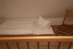 A single bed with a wooden headboard and a wooden chair to the right. - 4 in the country house “Am See” Neuensien (Ostseebad Sellin)