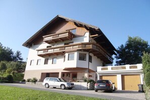 Ein mehrgeschossiges Wohngebäude mit geneigtem Dach, Balkonen und einer Garage.