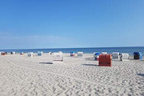 Ein Strand mit Reihen von Liegestühlen und Sonnenschirmen.