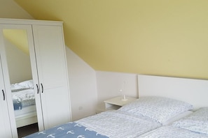A bedroom with a bed, a nightstand, and a wardrobe. - Holiday apartment with 1 bedroom (Hohwacht)