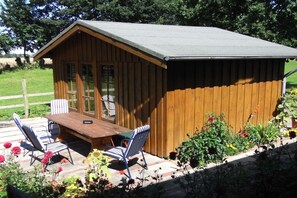 A wooden cabin with a porch, two chairs, and a table. - Holiday apartment with 2 bedrooms (Heringsdorf)