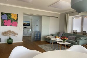 A modern living room with a sofa, a coffee table, and a painting of flowers on the wall. - Holiday apartment with 1 bedroom (Orth\/ Fehmarn)