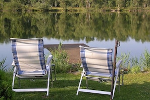 Two lawn chairs facing a calm lake with a dock in the background. - Holiday apartment with 1 bedroom (Zehdenick)