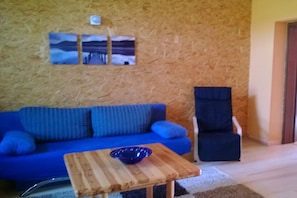 A room with a blue sofa, a wooden coffee table with a bowl, and a chair. - Holiday apartment with 1 bedroom (Zehdenick)