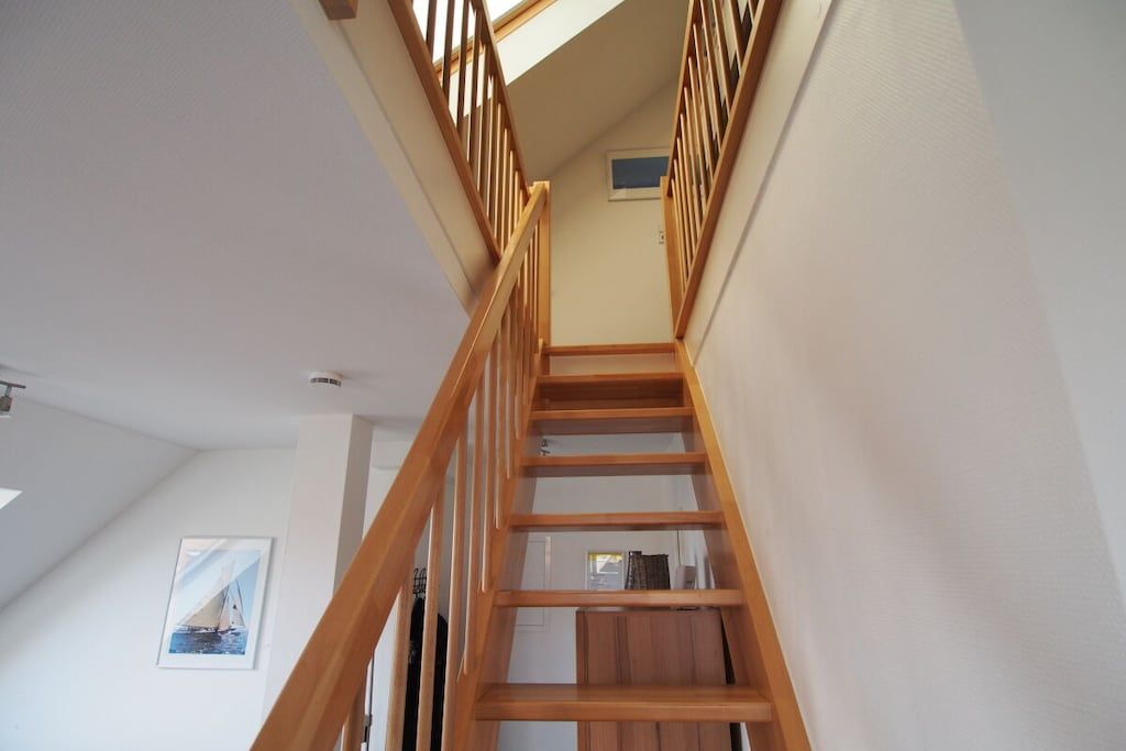 Eine Holztreppe mit Handlauf, die zu einer oberen Etage führt.