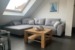 Ein modernes Wohnzimmer mit einer Eckcouch, einem Holztisch und einem Oberlicht.