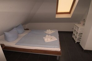 A single bed with a wooden frame, a skylight, and a white bedside table with a lamp. - Holiday apartment with 1 bedroom (Großenbrode)