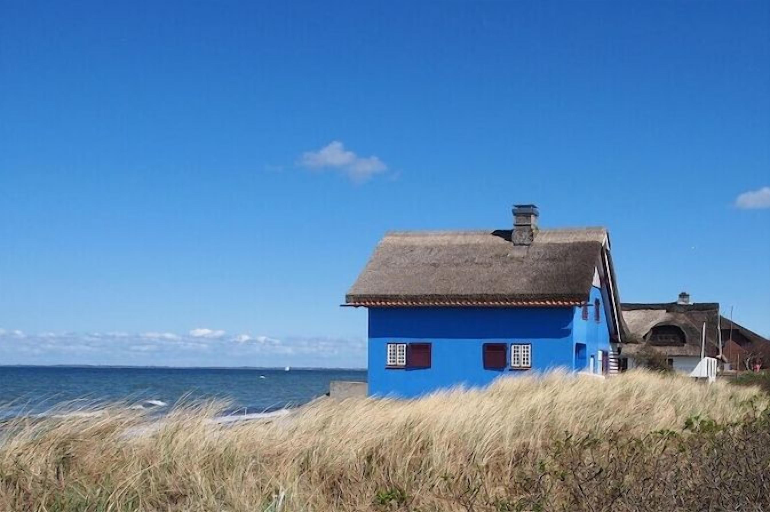 Um edifício costeiro com fachada azul e telhado de palha, localizado perto do mar.