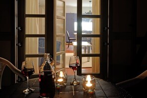 A table with a bottle and glasses of red wine, a candle, and a view through a glass door into a dining area. - Holiday apartment with 1 bedroom (Dranske)