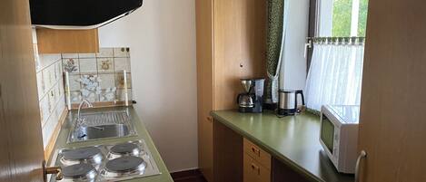 A compact kitchen with a gas stove, a coffee maker, and a microwave.