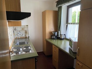 A compact kitchen with a gas stove, a coffee maker, and a microwave.