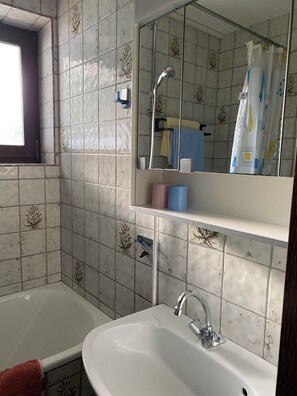Un baño con bañera, lavamanos, espejo y ventana.