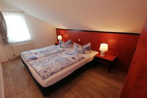 Ein Hotelzimmer mit einem großen Bett, zwei Nachttischen mit Lampen, einem hölzernen Kopfteil und einem Fenster mit Vorhängen.