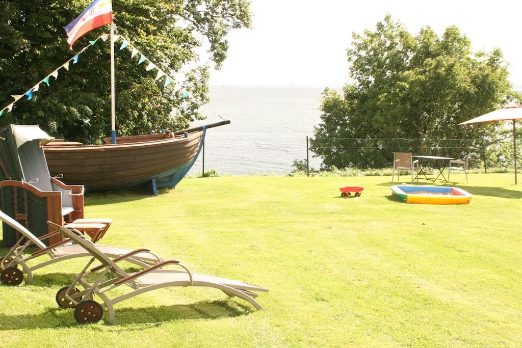 A grassy outdoor area with a boat, a table, and chairs.