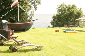 Eine grüne Rasenfläche mit einem Boot, einem Tisch und Stühlen.