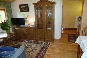 Ein Wohnzimmer mit Fernseher, Holzschrank und einem gemusterten Teppich.