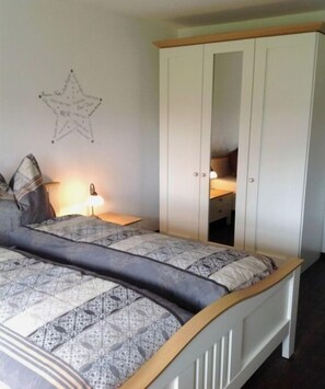 Een slaapkamer met een bed, een kast, een nachtkastje en een decoratie aan de muur.