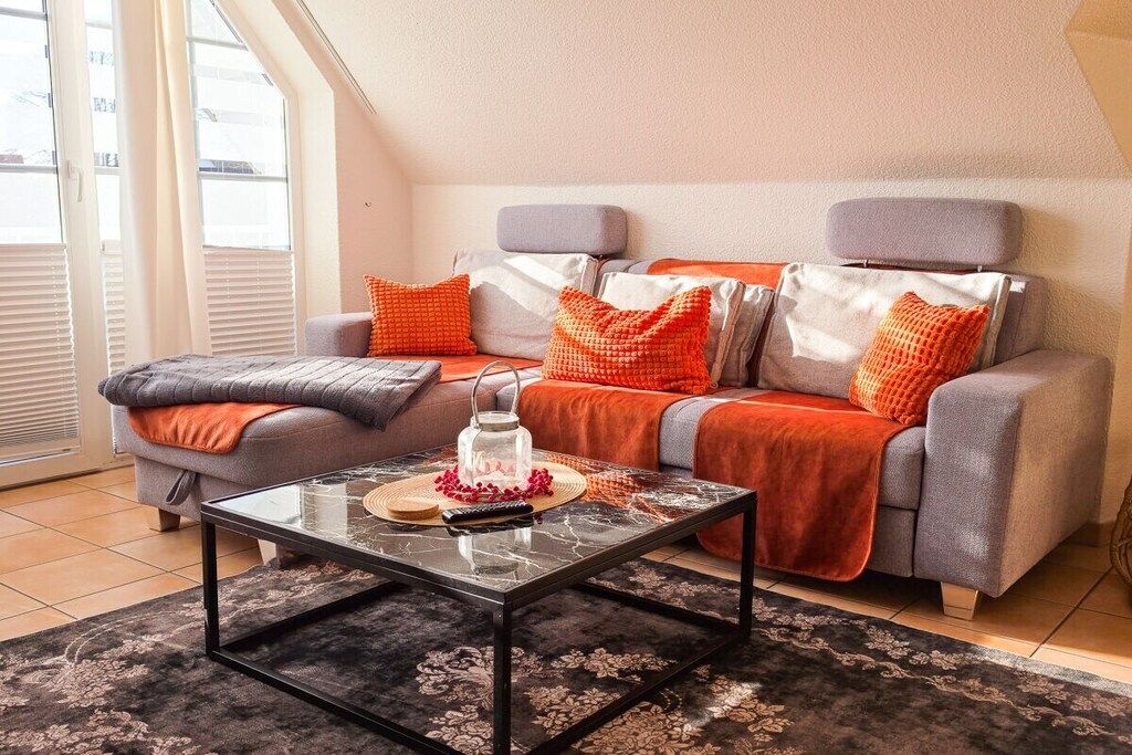 Un salon moderne avec un canapé, une table basse en verre et un tapis à motifs.