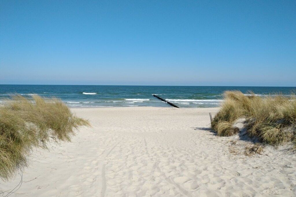 Een zandstrand met een heldere lucht en zee.