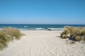Ein sandiger Strand mit klarem Himmel und dem Ozean.