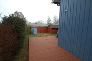 A wooden deck leading to a red garage with a blue building on the right. - Holiday home in Prerow with swimming pool (Prerow)