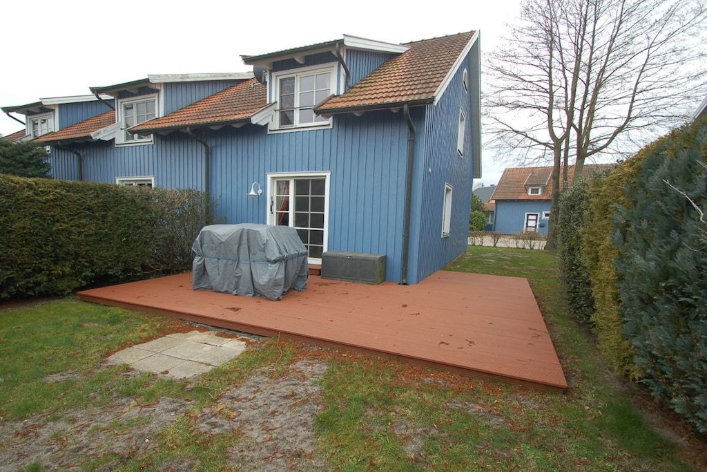 Ein zweistöckiges Haus mit überdachter Terrasse und rotem Dach.