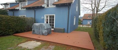 Ein zweistöckiges Haus mit überdachter Terrasse und rotem Dach.