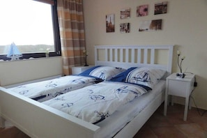 A bedroom with a bed, a nightstand, a window with curtains, and wall decorations. - Holiday apartment in Damp with swimming pool (Damp)