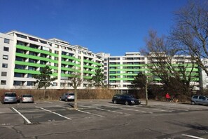 A multi-story parking structure adjacent to a building with green horizontal stripes. - Holiday apartment in Damp with swimming pool (Damp)