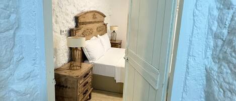 A bedroom with a bed, bedside table, lamp, and a dresser.