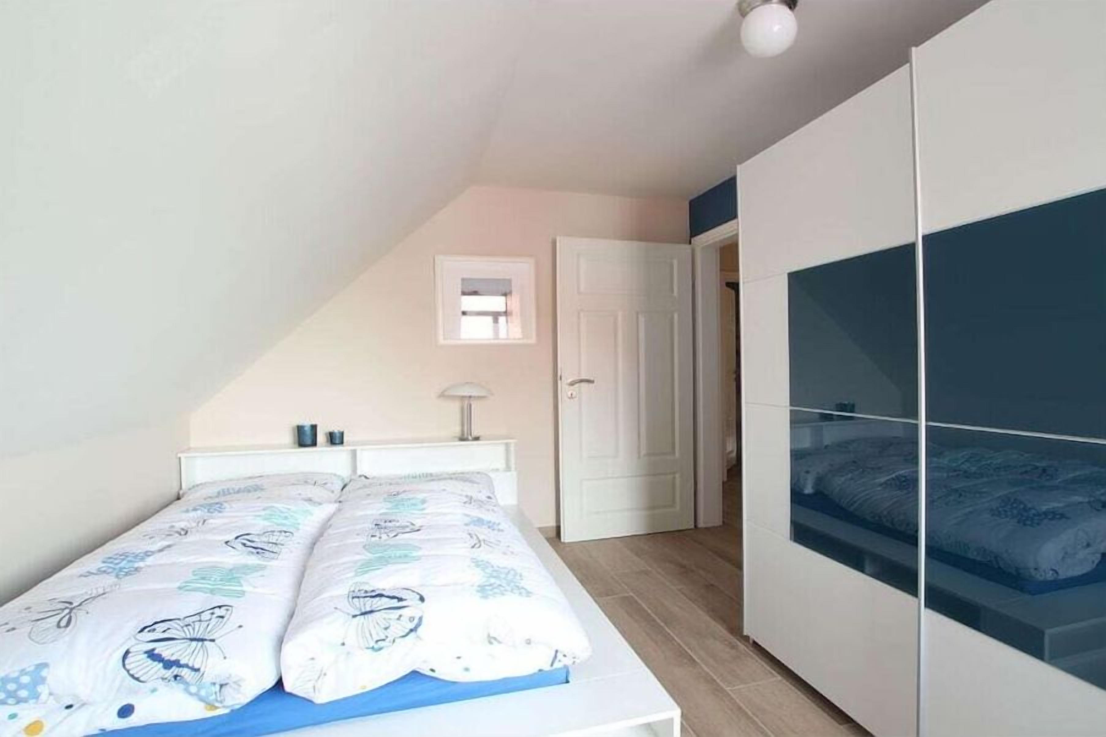 A bedroom with a bed, a wardrobe, a door, and a small window.