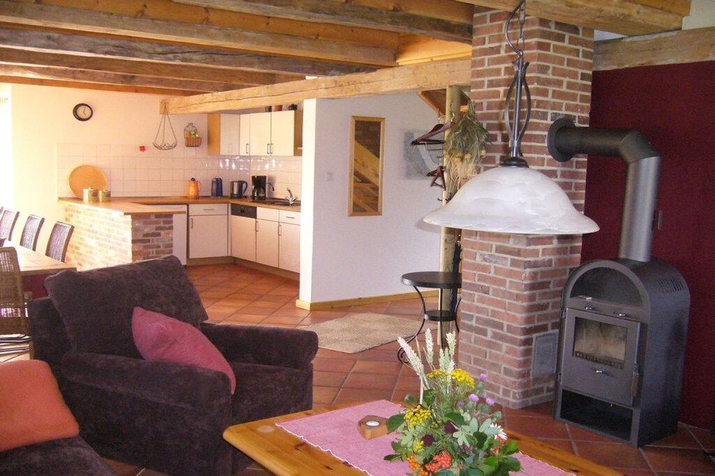 Un accogliente soggiorno con camino, una zona pranzo con cucina sullo sfondo e un’area salotto confortevole.
