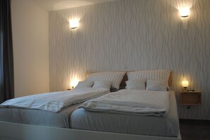 A double bed with two bedside tables, each with a lamp, in a room with wavy-patterned wallpaper. - Holiday apartment with 2 bedrooms (Kellenhusen)