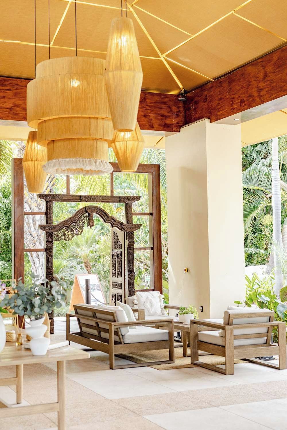 A room with a wooden bench seating area, a hanging light fixture, and a view of greenery outside.