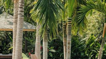 Un área de piscina con palmeras, sillas de descanso y un farol de piedra.