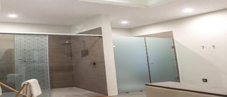 A modern bathroom with a glass shower enclosure, a vanity with a mirror, and a ceiling skylight.