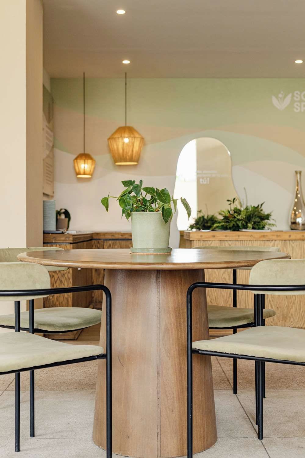 Un comedor con una mesa redonda de madera, dos sillas y lámparas colgantes.