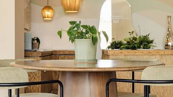 Un comedor con una mesa redonda de madera, dos sillas y lámparas colgantes.
