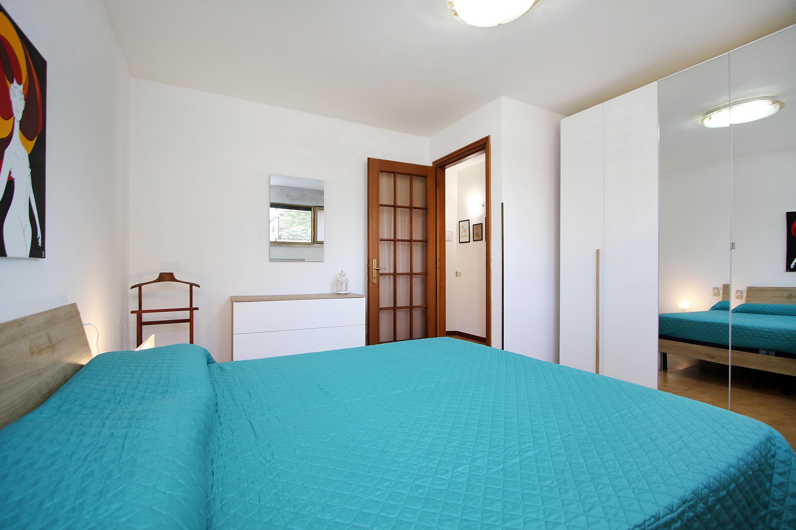 Une chambre à coucher avec un lit, une commode, un miroir et une porte.