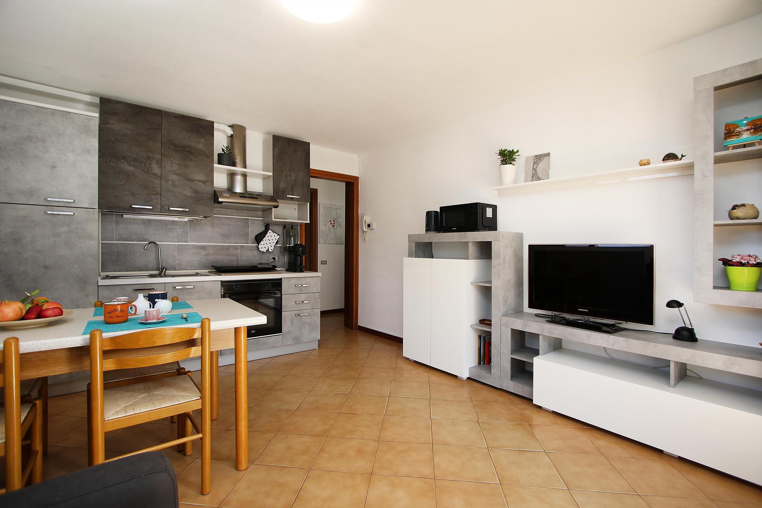 Angolo cottura compatto con zona pranzo, forno a microonde, macchina del caffè e televisione.