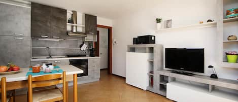 Una cocina compacta con comedor, microondas, cafetera y televisión.